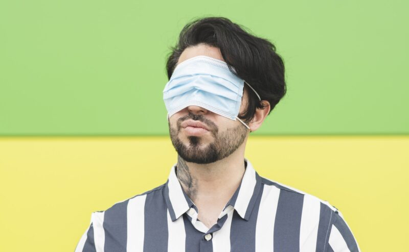 man covers his eyes with a medical mask
