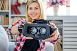 Smiling blond female showing virtual reality glasses.